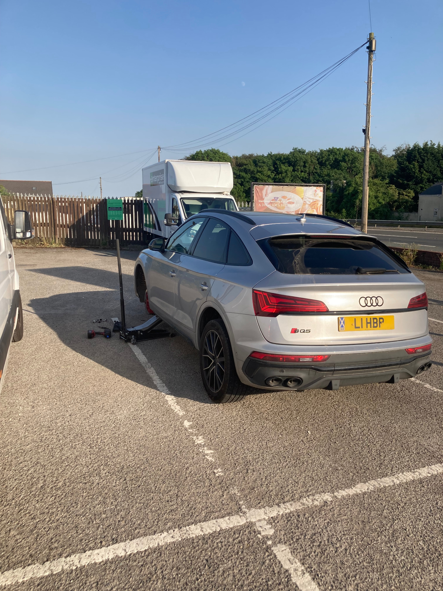 Wheel change on a silver Audi SQ5 in a car park